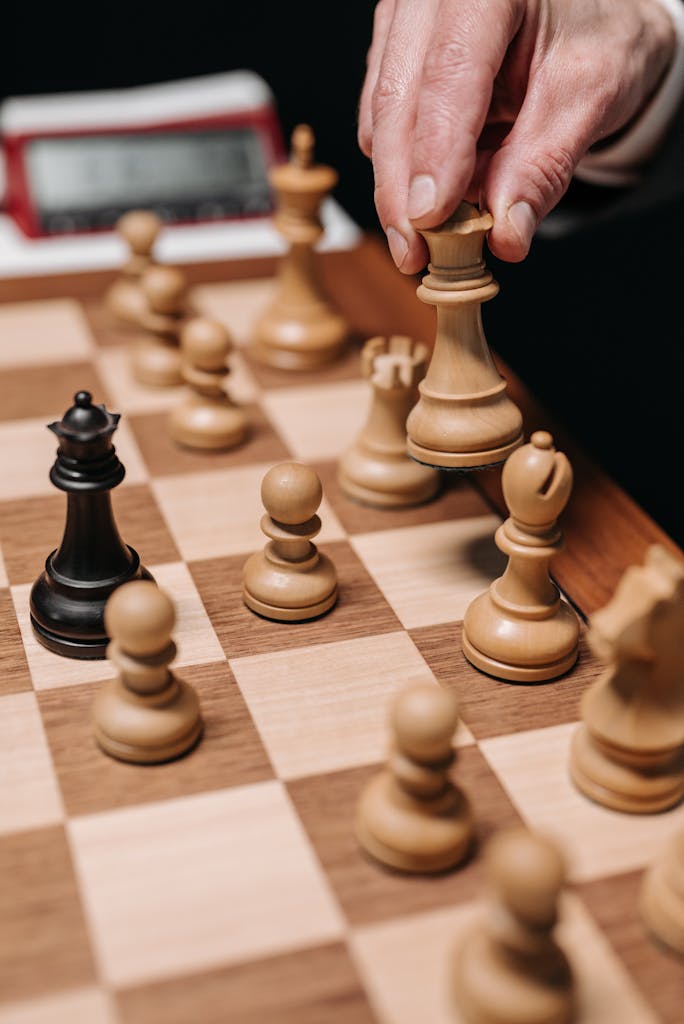 A close-up of a hand making a chess move during a game, emphasizing strategy and concentration.